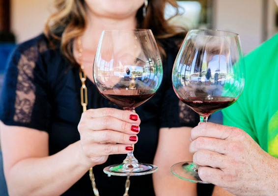 Two hands holding Emeritus Vineyards wine glasses